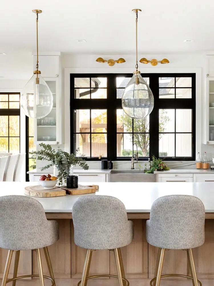 Kitchen with black-framed windows, oak island, and brass pendants