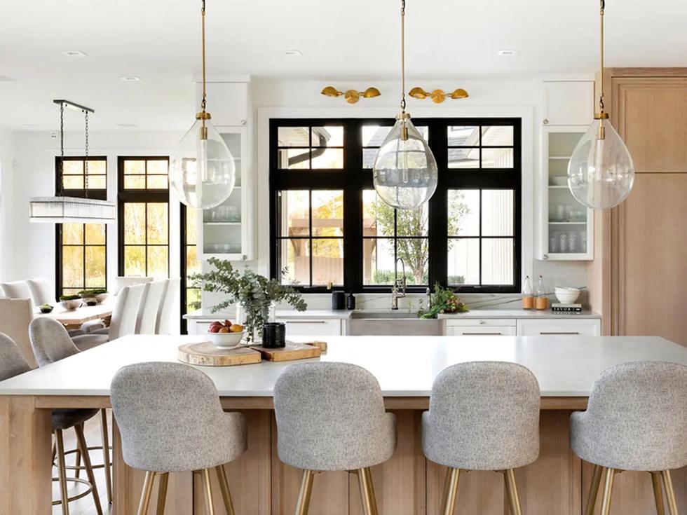 Kitchen with black-framed windows, oak island, and brass pendants